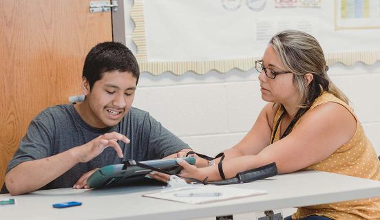 Ädelbrook employee helping a boy while he uses a tablet