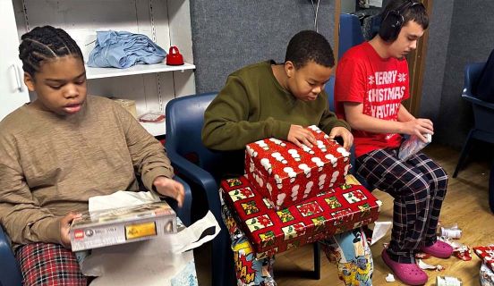 Boys wrapping Christmas presents with wrapping paper