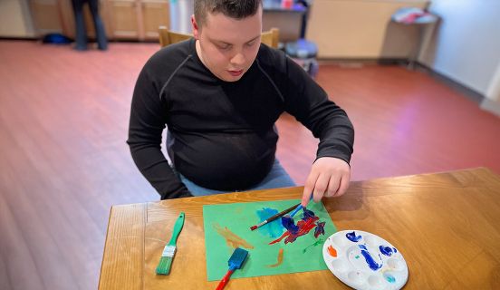 Young man sitting at a table and painting 