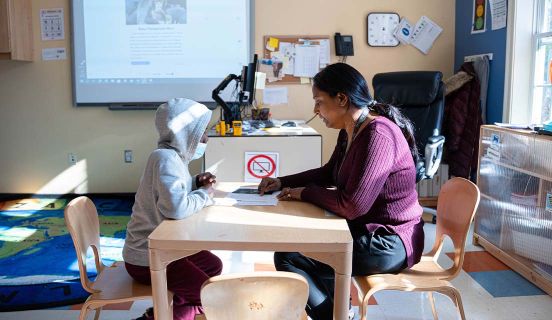 Adelbrook employee sitting at a table across from a young boy working on a worksheet