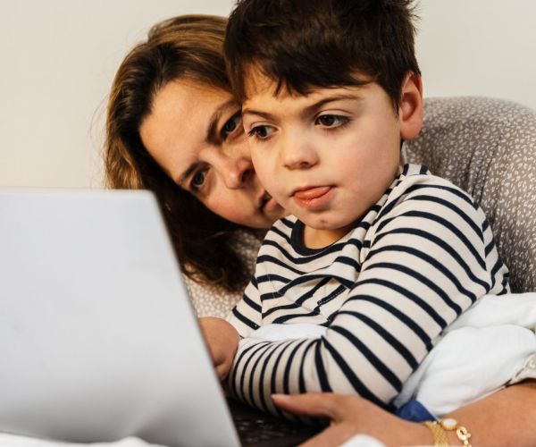 A child and their guardian looks at a laptop screen.