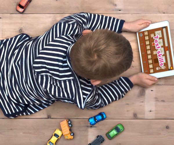 A little boy in a black and white stripped hoodie, using an app on a tablet. 