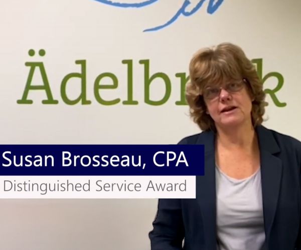 Susan Brosseau wearing a blazer standing by a wall reading "Adelbrook"