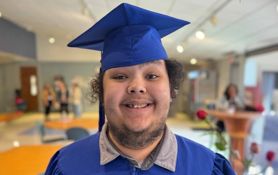 Young man smiling while wearing blue regalia